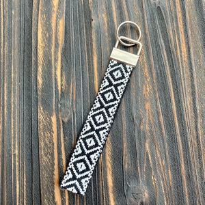 Close-up of hand-woven black and white geometric keychain on vintage wood background
