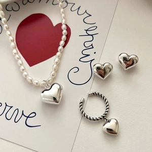 Flat lay of silver heart jewelry set with pearl necklace and earrings on a romantic card