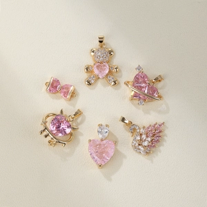 Pink zircon necklace charms including bear and heart shapes on beige background