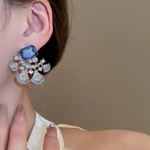 Macro detail of luxury floral drop earrings with blue gemstones and sparkling crystals