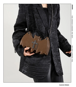 Gothic brown bat-shaped crossbody bag with metal cross detail worn by a model