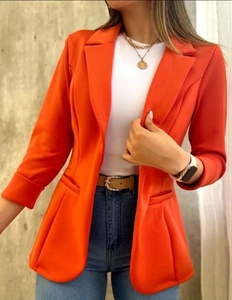 Primer plano detallado de una americana naranja de mujer con diseño clásico de cuello solapa