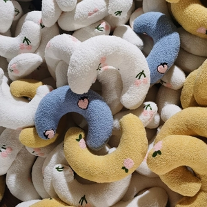 Pile of crescent shaped plush pet pillows with fruit embroidery in blue yellow and white