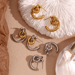 Three-tone C-shape knotted earrings in gold and silver finish on artistic white coral
