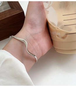 Macro di un bracciale a onde in argento minimalista al polso in un ambiente informale