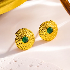 Macro view of vintage gold spiral texture earrings with inlaid green gemstone