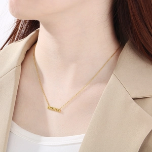 Close-up of 18K gold plated mama letter necklace on model's neck with beige suit