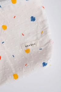 Detail of white Dotted Swiss fabric makeup bag with colorful abstract floral embroidery