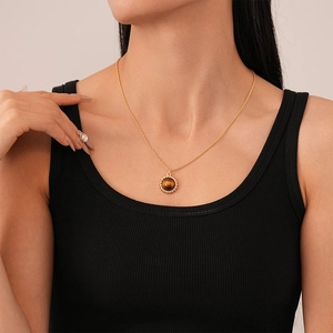 Close-up of a round faux tiger eye stone necklace with gold-plated rope border on a model