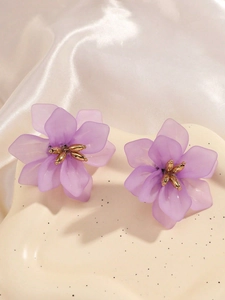 Close-up of lavender acrylic flower earrings with gold center on silk fabric