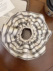 Detail of cream striped silk scrunchie on wooden desk with coffee cup scene