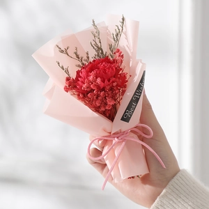 Detail of a handmade bouquet with red carnations and pink wrapping for best wishes