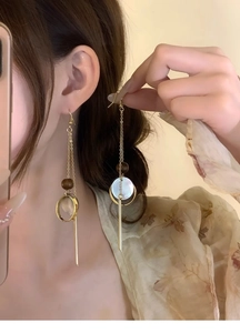Close-up of bohemian tassel earrings with wooden beads and shell inlay on ear hooks