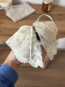 Macro shot of off-white polka dot mesh and embroidered lace bow hair clip details