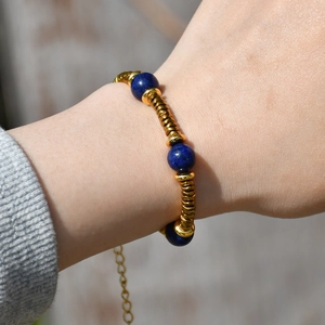 Detail of beaded gold bracelet featuring blue natural stones and adjustable chain on wrist