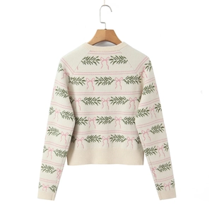 Close-up of knit texture with pine leaf and pink bow patterns on long sleeve top