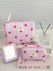 Close-up of pink strawberry quilted makeup bags with stripe patterns and woven labels
