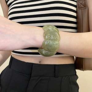 Detail of olive green acrylic wide bracelet with marble pattern worn by a model