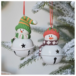 Christmas snowman bells ornaments with knitted hats hanging on a snowy tree branch