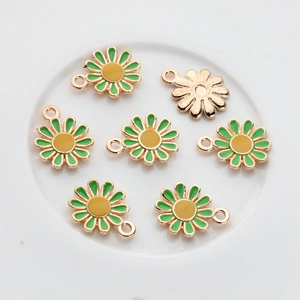 Detail of small daisy alloy charms with green enamel petals and golden hanging loops