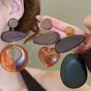Detailed close-up of mixed wood and resin drop earrings in heart and circular styles