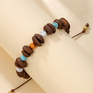 Close-up of beaded coffee bean bracelet with turquoise and wooden beads on a prop