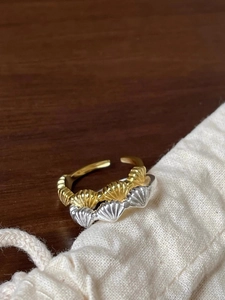 Makroaufnahme von silbernen und goldenen Muschelringen auf einem Leinenbeutel auf Holz