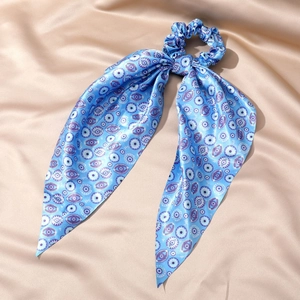 Blue silk hair scrunchie with evil eye pattern and long ribbons on beige silk fabric