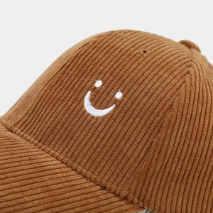 Dettaglio del cappello da baseball in velluto a coste color caramello con ricamo a sorriso