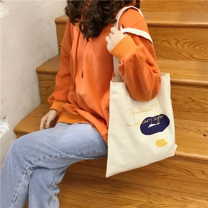 Detail of white canvas tote bag with artistic color blocks and letter print on shoulder