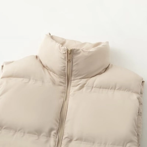Minimalist beige sleeveless puffer vest featuring a high collar and sleek metal zipper