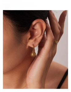 Macro detail of French vintage gold sun pendant earrings and sparkling diamond ring