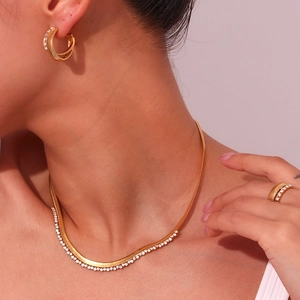 Detail of 18K gold plated jewelry set with herringbone necklace and crystal ring