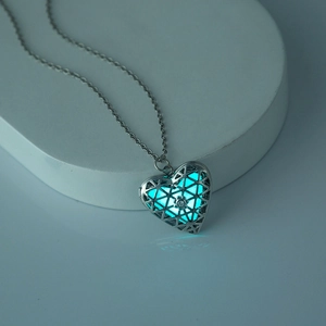 Dettaglio del ciondolo a cuore argento con luce blu su un supporto geometrico