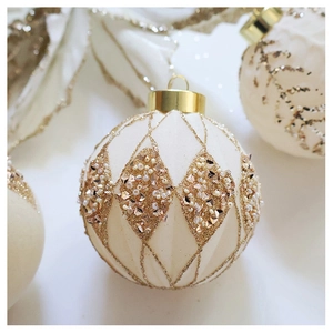 Macro shot of cream Christmas ball featuring gold glitter grid and champagne beads decor