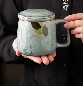 Close-up of celadon crackle glaze ceramic tea mug with hand-painted rabbit and lid