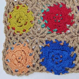 Macro detail of hand-crocheted floral squares in vibrant colors with fine stitching
