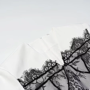 Close-up of white V-neck dress featuring contrast black eyelash lace and invisible zipper
