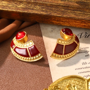 Macro shot of vintage Christmas red enamel earrings with gold base on retro paper