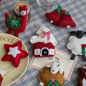 Handmade Christmas felt ornaments with red alpaca and stars on checkered tablecloth