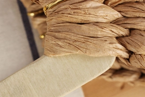 Detailed close-up of woven paper rope bag with round wood handle and gold metal rings