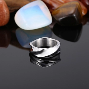 Macro detail of silver irregular twisted stainless steel ring on black reflective surface