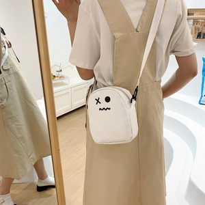 Détail d'un sac bandoulière en toile blanche avec un imprimé smiley dessin animé minimaliste