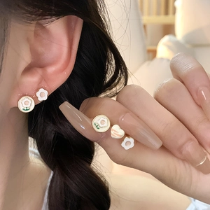Detalle de pendientes de plata S925 con flores de esmalte blanco y bordes verdes modernos