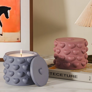 Detail of heart-patterned candle jars in matte pink and purple on marble table
