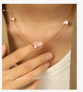 Close-up of rose gold necklace featuring three pink heart pendants on a female model