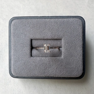 Emerald cut moissanite ring in rose gold setting displayed in a grey velvet jewelry box