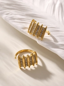 Detailed view of two gold open rings with white zircon stones on a textured surface
