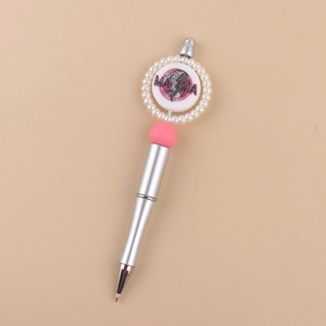 Detail of silver beaded pen with pearl MAMA charm and pink ball on beige background