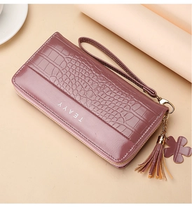 Detail of purple-pink long wallet with crocodile texture, wrist strap and tassel